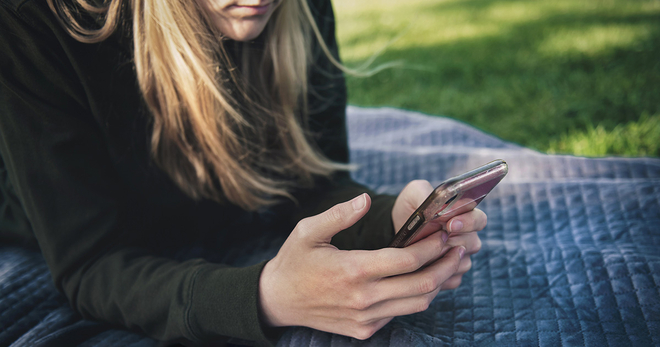 Girl texting on blanket 